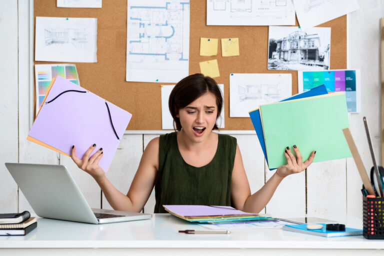 Upset young beautiful businesswoman sitting at workplace. Office background.
